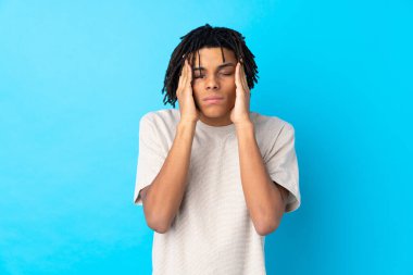 Genç Afrikalı Amerikalı, mavi arka planda, baş ağrısı var.