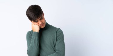 Soyutlanmış mavi arkaplan üzerinde yakışıklı bir adam. Yorgun ve sıkılmış ifadesi var.