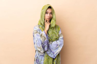 Hintli kadın bej arka planda izole edilmiş ve düşünüyor