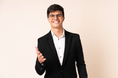 İzole edilmiş bej arka plan el sıkışması üzerine iş adamı.