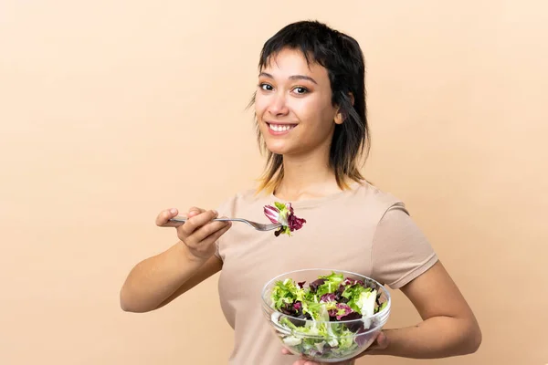Young Uruguayan woman with salad over isolated wall