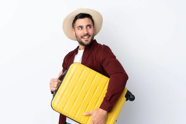 度假时 年轻英俊的男子背着旅行箱 头戴一顶帽子 背景是白色的 与外界隔绝 — 图库照片