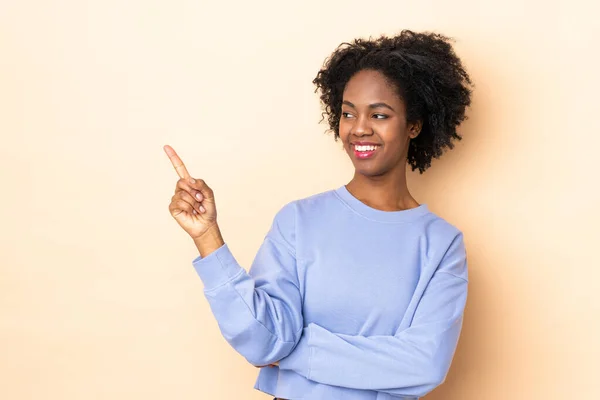 Jonge Afro Amerikaanse Vrouw Geïsoleerd Beige Achtergrond Wijzend Naar Zijkant — Stockfoto