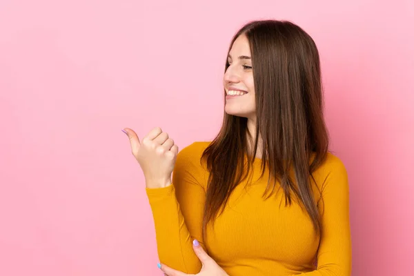 Mujer Joven Caucásica Aislada Sobre Fondo Rosa Apuntando Hacia Lado —  Fotos de Stock