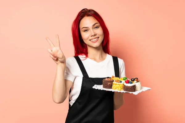 Pastry Chef Holding Muffins Isolated Pink Background Showing Victory Sign — Stock Photo, Image