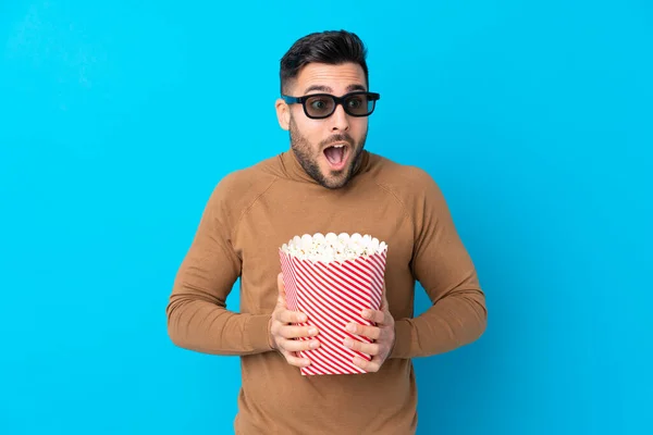 Młody Przystojny Mężczyzna Zaskoczony Okulary Trzymając Duży Wiadro Popcorns — Zdjęcie stockowe