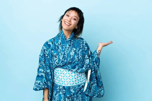 Mujer Joven Usando Kimono Sobre Fondo Azul Aislado Sosteniendo Espacio —  Fotos de Stock