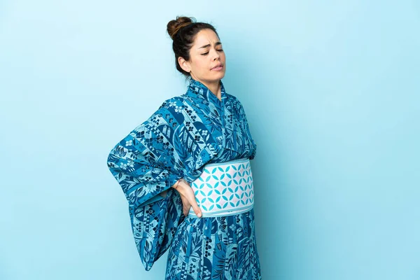 Woman wearing kimono over isolated background suffering from backache for having made an effort