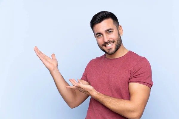 Jovem Homem Bonito Com Barba Sobre Fundo Azul Isolado Estendendo — Fotografia de Stock