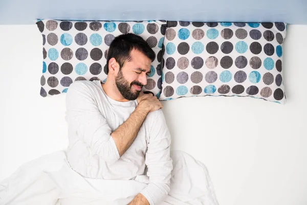 Man in bed in top view suffering from pain in shoulder for having made an effort