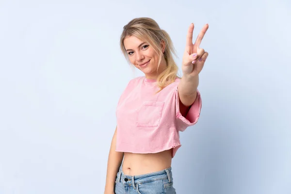 Mujer Rubia Sobre Fondo Azul Aislado Sonriendo Mostrando Signo Victoria —  Fotos de Stock