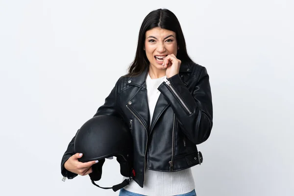 Young woman holding a motorcycle helmet over isolated white background nervous and scared
