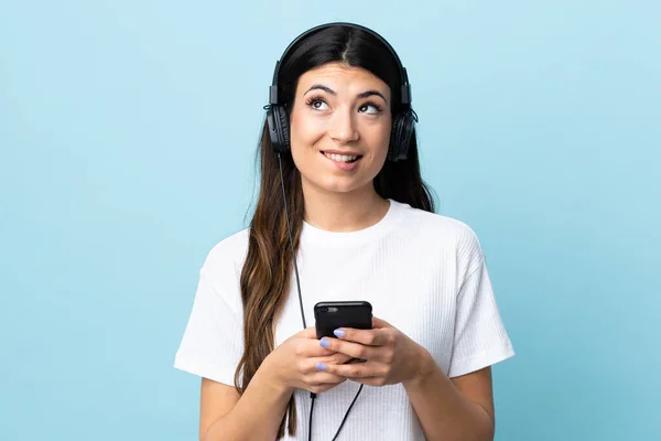 Jeune Fille Brune Sur Fond Bleu Isolé Écoutant Musique Avec — Photo