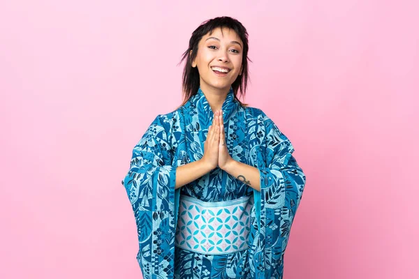 Ung Kvinna Bär Kimono Över Isolerad Blå Bakgrund Håller Handflatan — Stockfoto