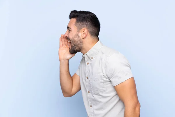 Jovem Homem Bonito Com Barba Sobre Fundo Azul Isolado Gritando — Fotografia de Stock