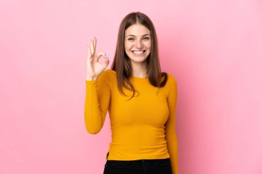 Pembe arka planda izole edilmiş beyaz bir kadın parmaklarıyla tamam işareti gösteriyor.