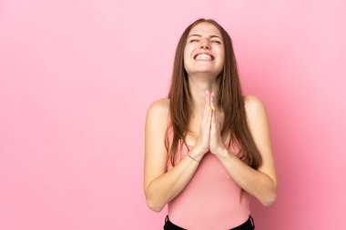 Pembe arka planda izole edilmiş genç beyaz kadın avuç içlerini bir arada tutuyor. İnsan bir şey ister.