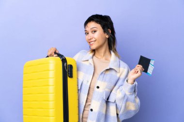 Genç Uruguaylı kadın izole edilmiş mor bir geçmişi var. Bavul ve pasaportla tatilde.