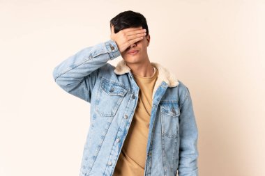 İzole edilmiş bej arka planda yakışıklı bir adam. Gözlerini elleriyle kapatıyor. Bir şey görmek istemiyorum.