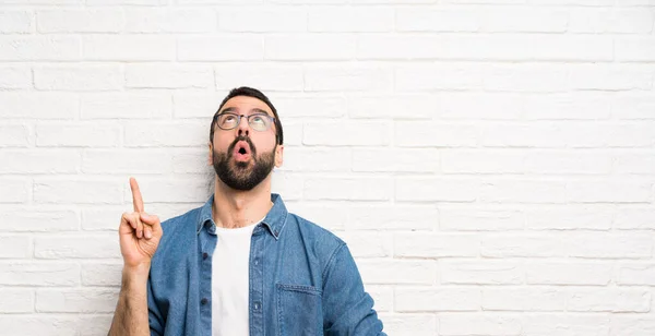 Hombre Guapo Con Barba Sobre Pared Ladrillo Blanco Apuntando Hacia —  Fotos de Stock