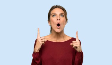 Sarışın kadın mavi arka planı işaret ediyor ve şaşırıyor.