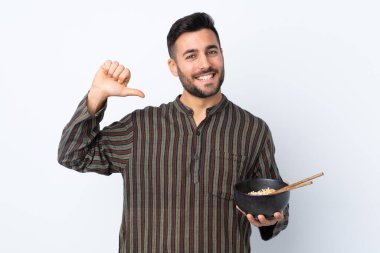 Tecrit edilmiş genç adam elinde çubukla bir kase erişte tutarken gururlu ve kendini beğenmiş.