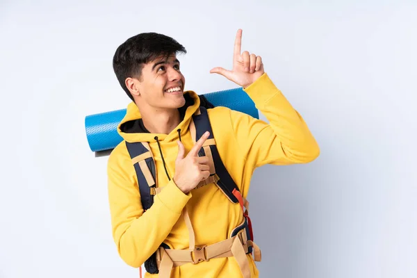 Молодий Альпініст Великим Рюкзаком Над Ізольованим Синім Тлом Вказує Індексний — стокове фото