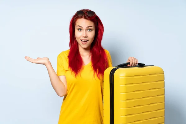 带着一个蓝色背景的手提箱的旅行女孩 脸上带着震惊的表情 — 图库照片