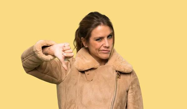 Szőke Egy Kabát Mutatja Hüvelykujját Lefelé Negatív Kifejezés Izolált Sárga — Stock Fotó