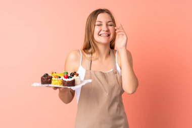 Ukraynalı aşçı pembe arka planda izole edilmiş bir kek tutuyor.