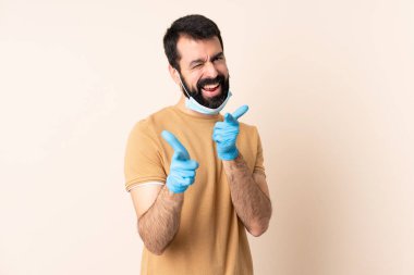 Sakallı beyaz bir adam. Koronavirüsten koruyor. Maskeli ve eldivenli.