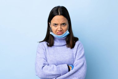 Genç esmer, melez bir kadın. Koronavirüsten koruyor. Maske ve eldivenlerle.