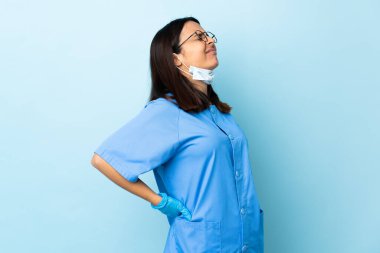 Tecrit edilmiş mavi arkaplan üzerinde cerrah kadın çaba sarf ettiği için sırt ağrısı çekiyor.