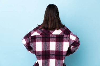 Genç esmer, melez bir kadın. Koronavirüsten korunuyor. Maske ve eldivenlerle arka planda mavi bir arka plan var.