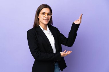 Mor arka planda izole edilmiş bir iş kadını. Davet edilmek için ellerini yana uzatıyor.