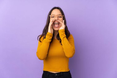 Mor arka planda izole edilmiş genç bir ırk kadını bağırıyor ve bir şeyler söylüyor.