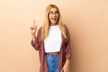 Genç Uruguaylı sarışın kadın soyutlanmış arka planda yukarı bakıyor ve şaşırıyor