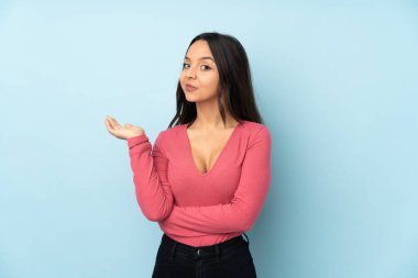 Mavi arka planda izole edilmiş genç melez kadın bir şeyi anlamadığı için mutsuz.