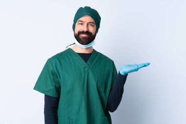 Yeşil üniformalı bir cerrah, izole edilmiş bir zeminde fotokopi makinesi ilanı takmak için avucunun içinde hayali bir şey tutuyor.
