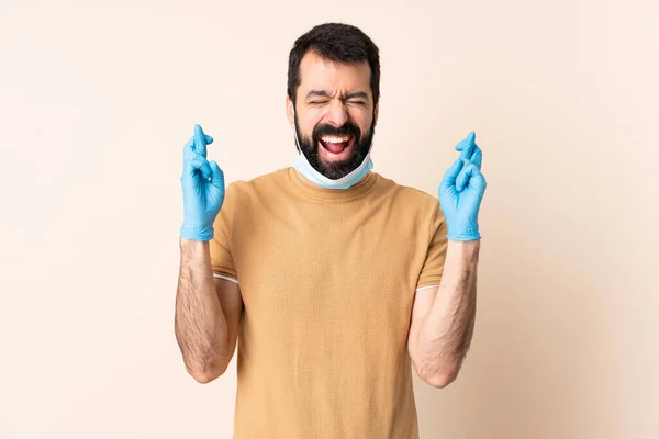 一个白种人 留着胡子 戴着面具 戴着手套 戴在孤立的背景上 手指头交叉在一起 保护自己不受考拉威斯的伤害 — 图库照片