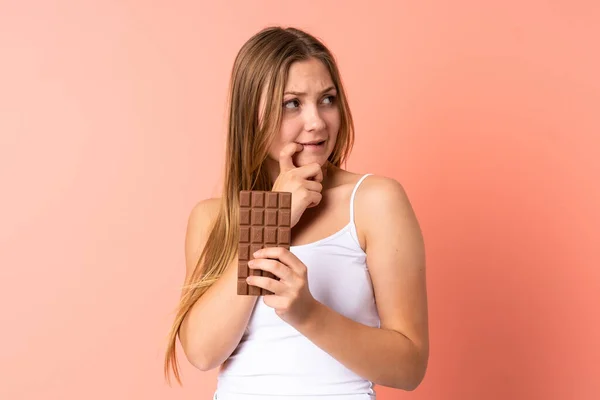 Teenager Ukrainian Girl Isolated Pink Background Taking Chocolate Tablet Having — Stock Photo, Image