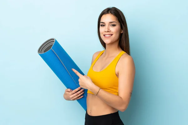 Mujer Deportiva Joven Con Estera Aislada Sobre Fondo Azul Apuntándola — Foto de Stock