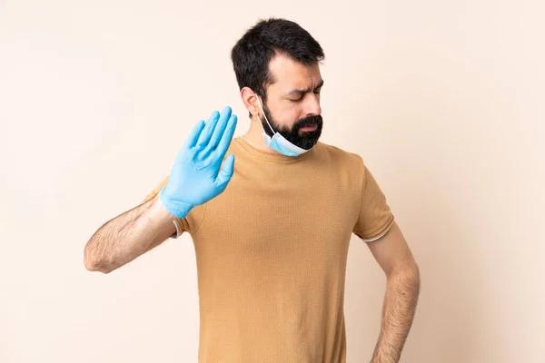 一个白种人 留着胡子 戴着面具和手套 在孤立的背景下保护自己不受考拉威斯的伤害 — 图库照片