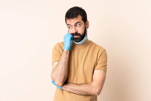 一个白种人 留着胡子 戴着面具 戴着手套 在孤立的背景下 带着疲惫而无聊的表情 保护自己不受头皮的侵害 — 图库照片