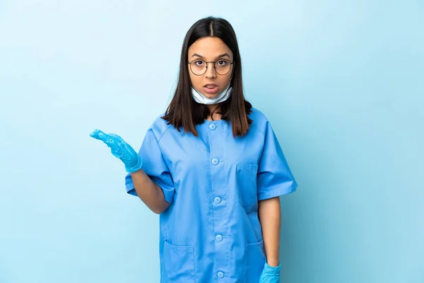 孤立的蓝色背景下的女外科医生做着怀疑的手势 — 图库照片