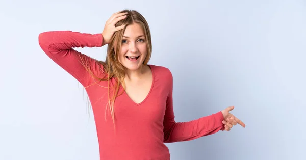 Nastolatka Ukraińska Dziewczyna Odizolowany Niebieskim Tle Zaskoczony Wskazując Palcem Bok — Zdjęcie stockowe