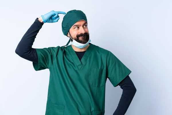 Cirurgião Homem Uniforme Verde Sobre Fundo Isolado Com Dúvidas Coçar — Fotografia de Stock
