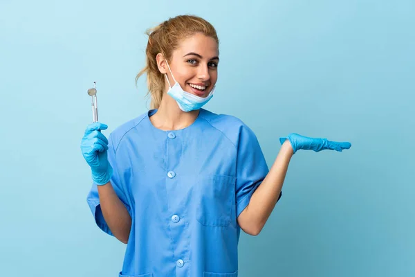 Jovem Dentista Segurando Ferramentas Sobre Fundo Azul Isolado Segurando Copyspace — Fotografia de Stock