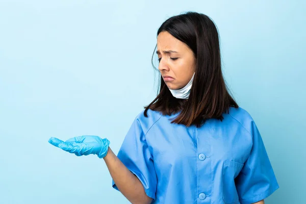 Chirurg Žena Přes Izolované Modré Pozadí Držení Copyspace Pochybnostmi — Stock fotografie