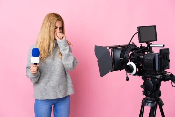 Reporter woman holding a microphone and reporting news over isolated pink background coughing a lot